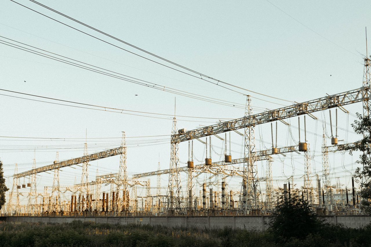 A wide view of an industrial electrical substation with power lines and towers outdoors.